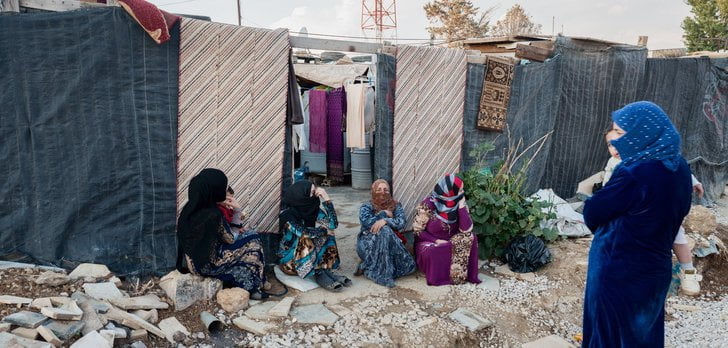 Four woman sitting in a refugee camp in Lebanon.