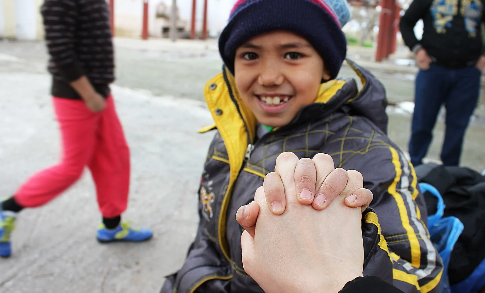 Young refugee boy holding someone's hand