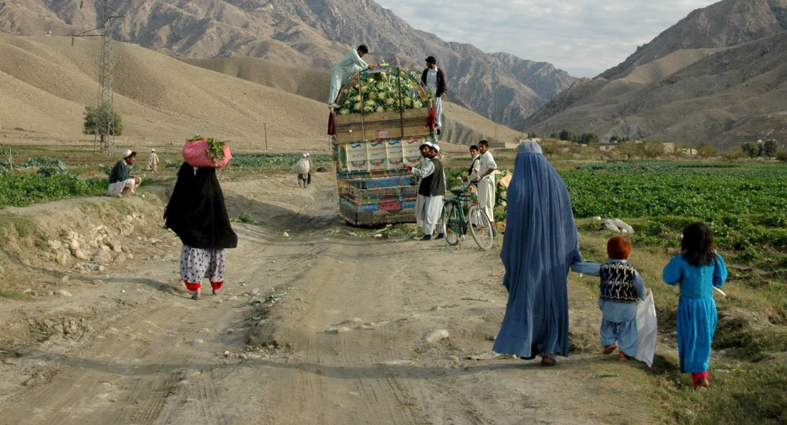 A woman and her family walking behind a cart in rural Afghanistan