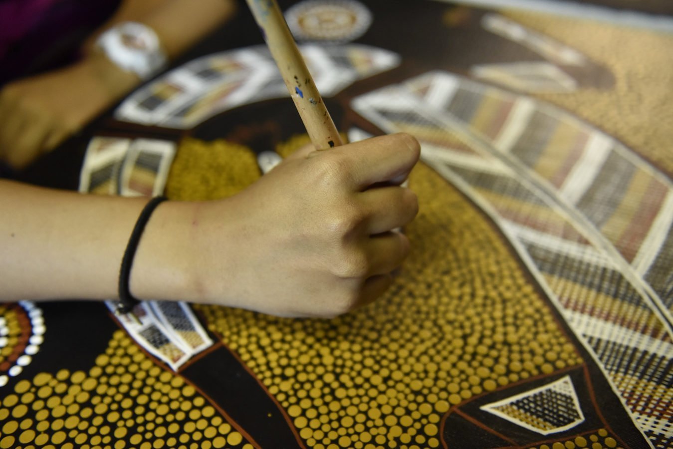 A girl making Aboriginal artwork