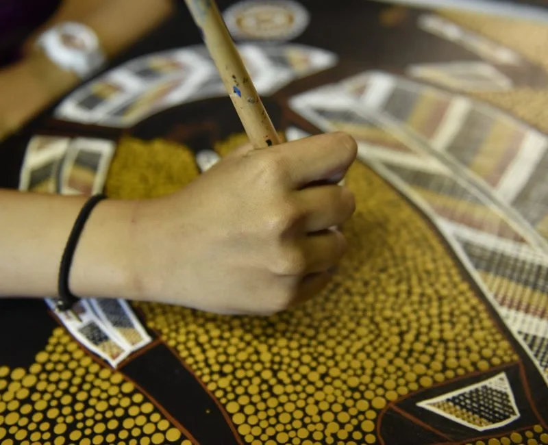 A girl making Aboriginal artwork