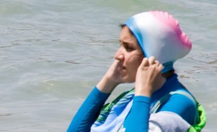 A woman in the ocean wearing a burkini.
