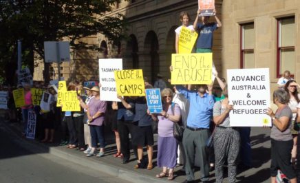 Activists hold up placards protesting Australia's refugee policies.
