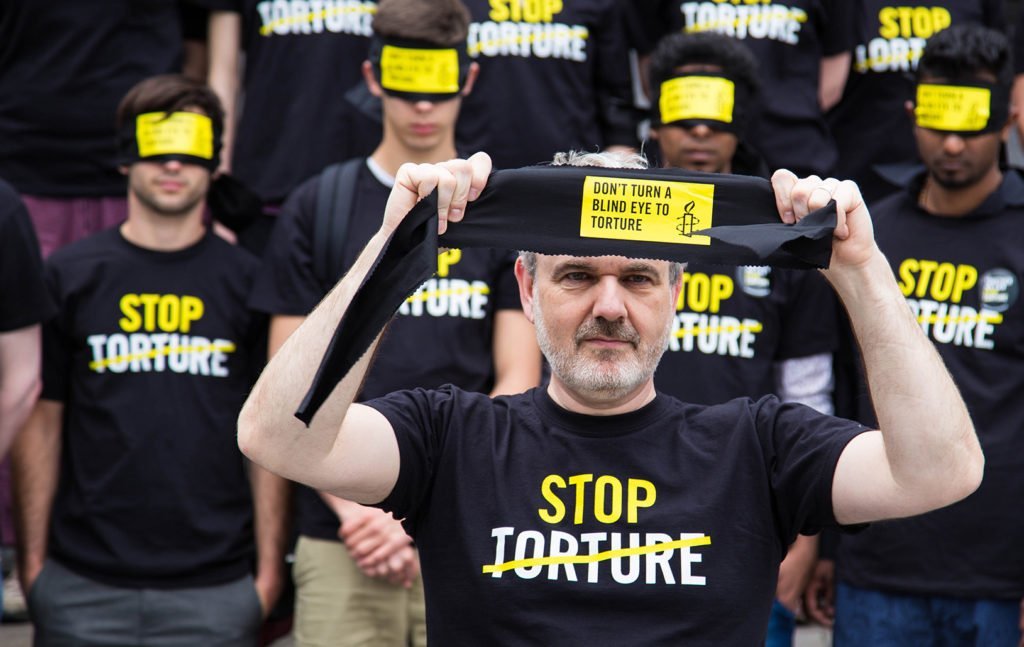 Amnesty protesters with Stop Torture T-shirts and blindfolds at a rally.