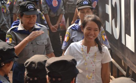 Student activist Phyoe Phyoe Aung smiling while she is escorted by policewomen
