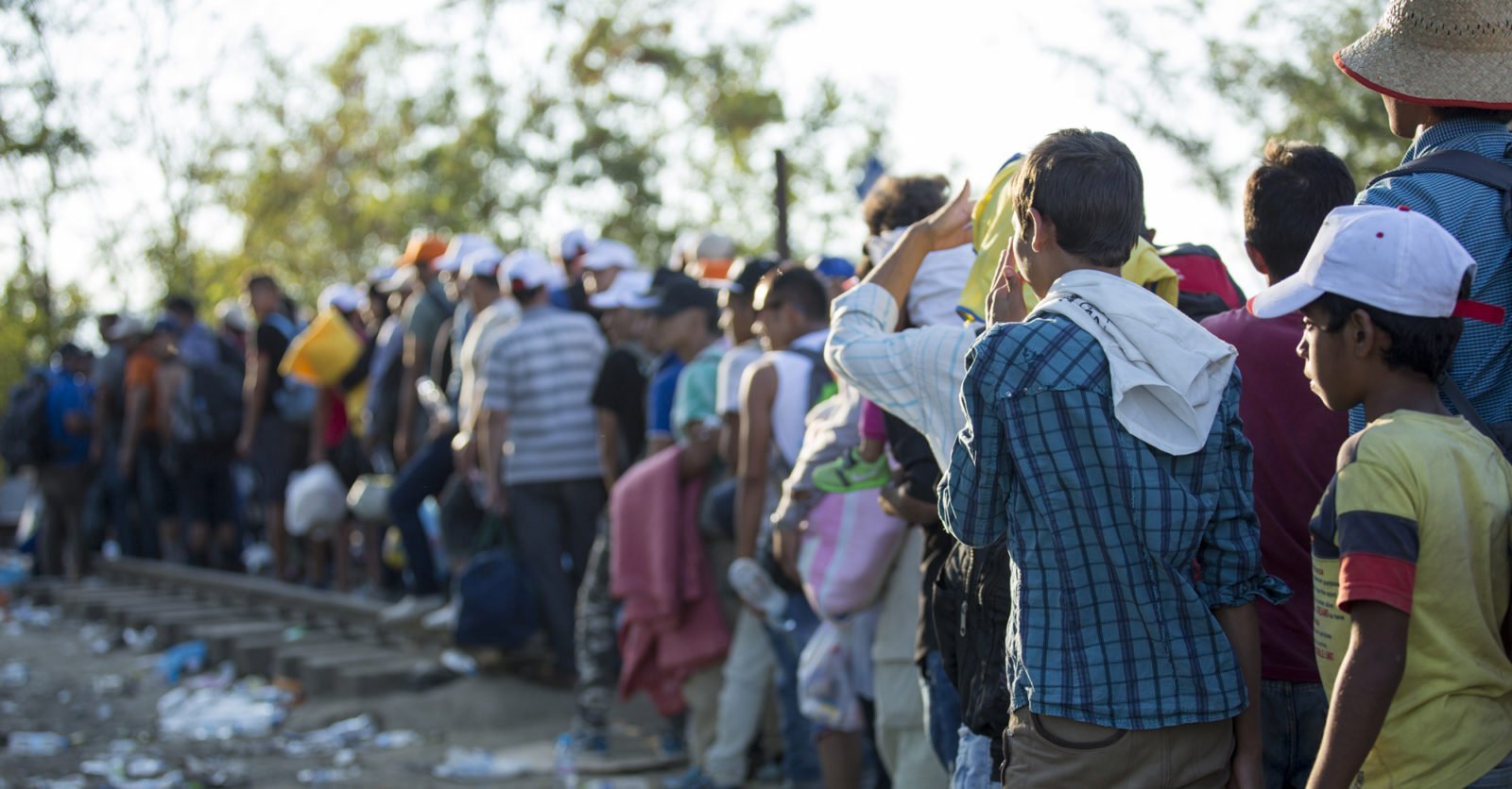 A long line of refugees, many holding personal possessions, waiting at the Greece-Macedonian border.