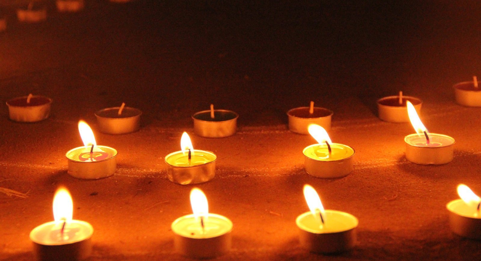 Close-up of some small lit candles lined up in a row.