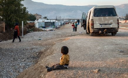 Syrian boy sits on a roadside in Lebanon