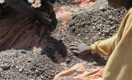 Charles, a 13 year old boy, sorts stones containing cobalt with his father, on the shore of Lake Malo, Democratic Republic of the Congo. May 2015.