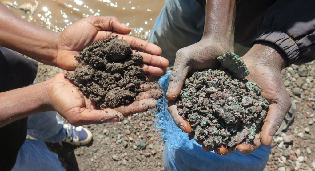 Artisanal miners hold up handfuls of cobalt ore (left) and copper ore (right). Democratic Republic of the Congo, May 2015.