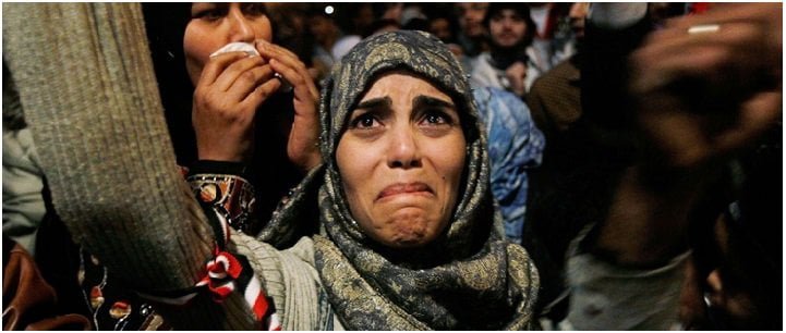 A woman cries at a protest with her arms raised in Tahrir Square after it is announced that Egyptian President Hosni Mubarak was giving up power. Tahrir Square, Egypt, 2011.