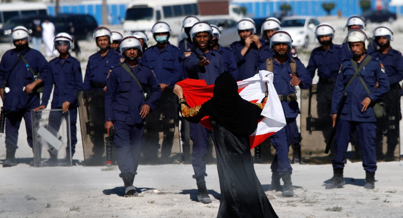 An anti-government protester holds a flag in front of a line of police in Bahrain.