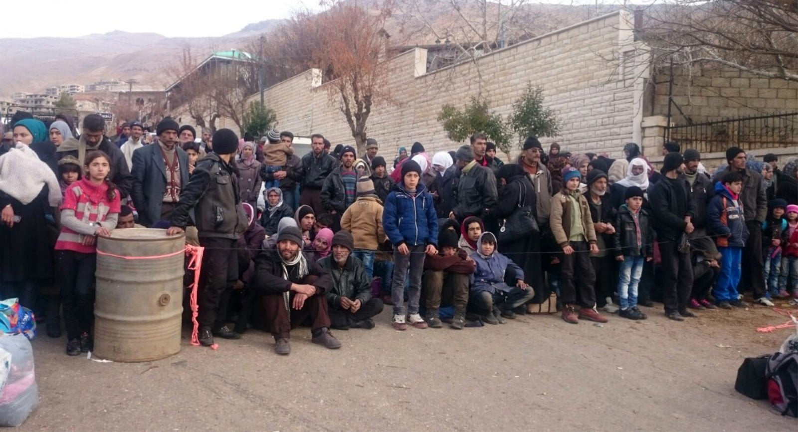 Syrians wait for the arrival of an aid convoy on January 11, 2016 in the besieged town of Madaya.