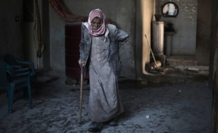 Syrian Abu Mohammed, covered with dust from explosions, walks in his home supported by a cane following reported air strikes