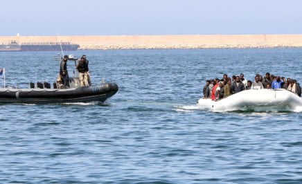 Libyan coast guards escort a boat along the coastline.