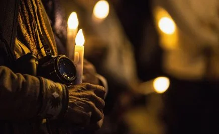 An activist holds a camera and a candle at a vigil