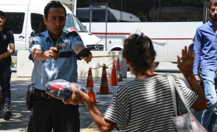 A Turkish police points his gun to a woman, asking her to leave the package she is carrying, in front of the courthouse in Ankara, on July 18, 2016, as some 7500 people have been detained in Turkey and almost 9000 officials sacked three days after a failed coup which has stunned the country.