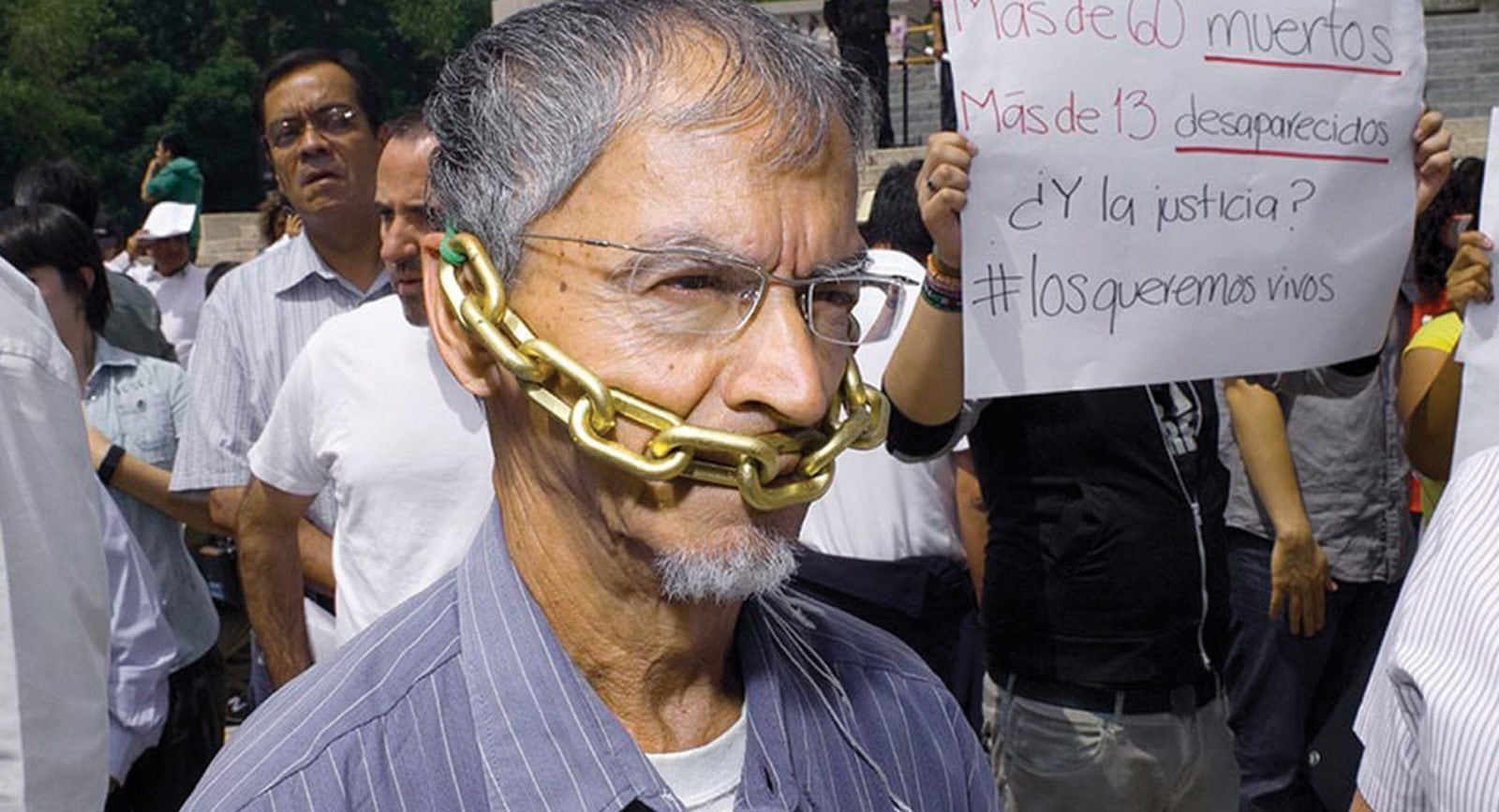 A man with a chain over his mouth protesting attacks on journalists