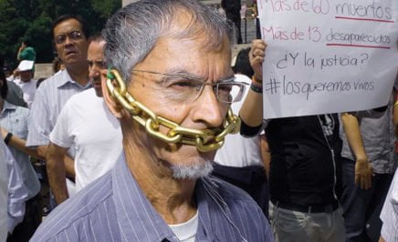 A man with a chain over his mouth protesting attacks on journalists