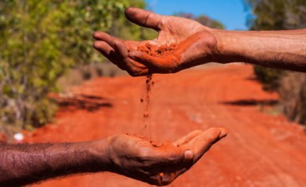 Red sand pouring through hands in the Australian desert