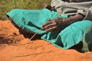 Aboriginal woman making a sand painting in NT, Australia.