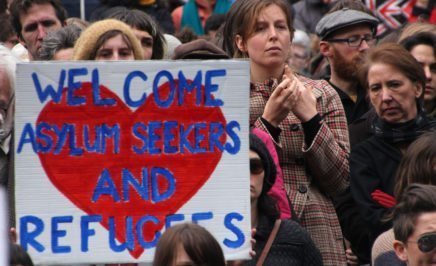 A protester holds a sign reading 'Welcome asylum seekers and refugees'