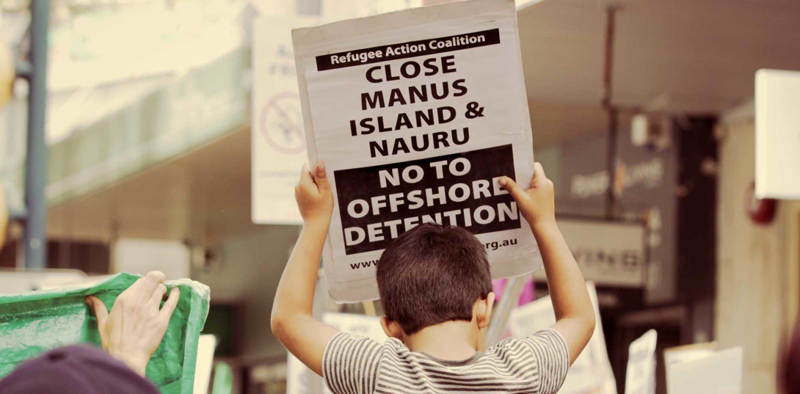 Boy holds a close Manus and Nauru sign