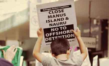 Boy holds a close Manus and Nauru sign