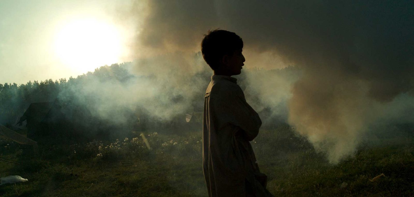 A young boy walks through clouds of smoke at the Sheikh Shehzad camp