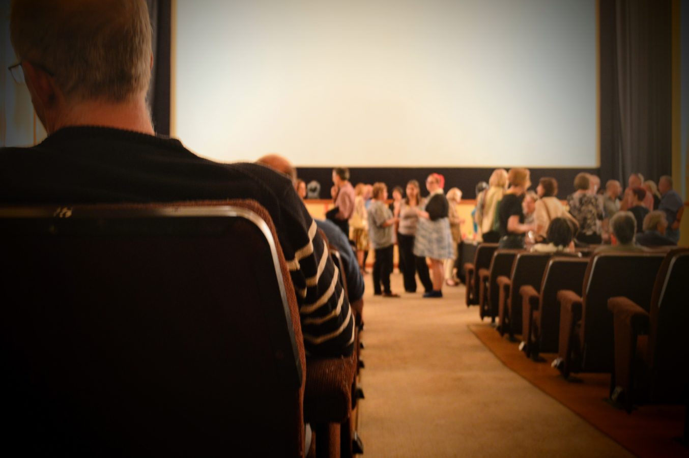people seated and standing in a cinema