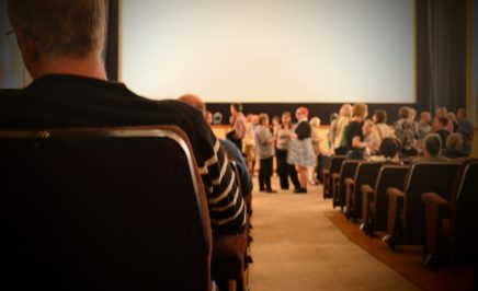 people seated and standing in a cinema