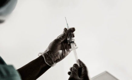 A gloved hand holding a syringe. © Amnesty International