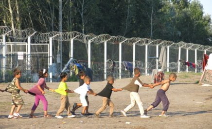Child refugees playing in a line holding each other