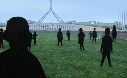 Cardboard silhouettes of children on the lawn outside parliament house