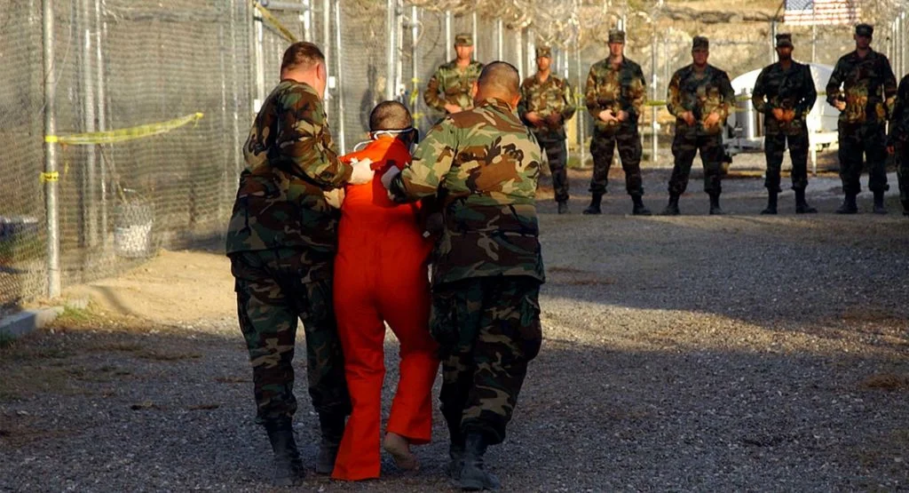 Guantanamo Camp X-Ray. U.S. Army Military Police escort a detainee to his cell in Camp X-Ray at Naval Base Guantanamo Bay, Cuba.