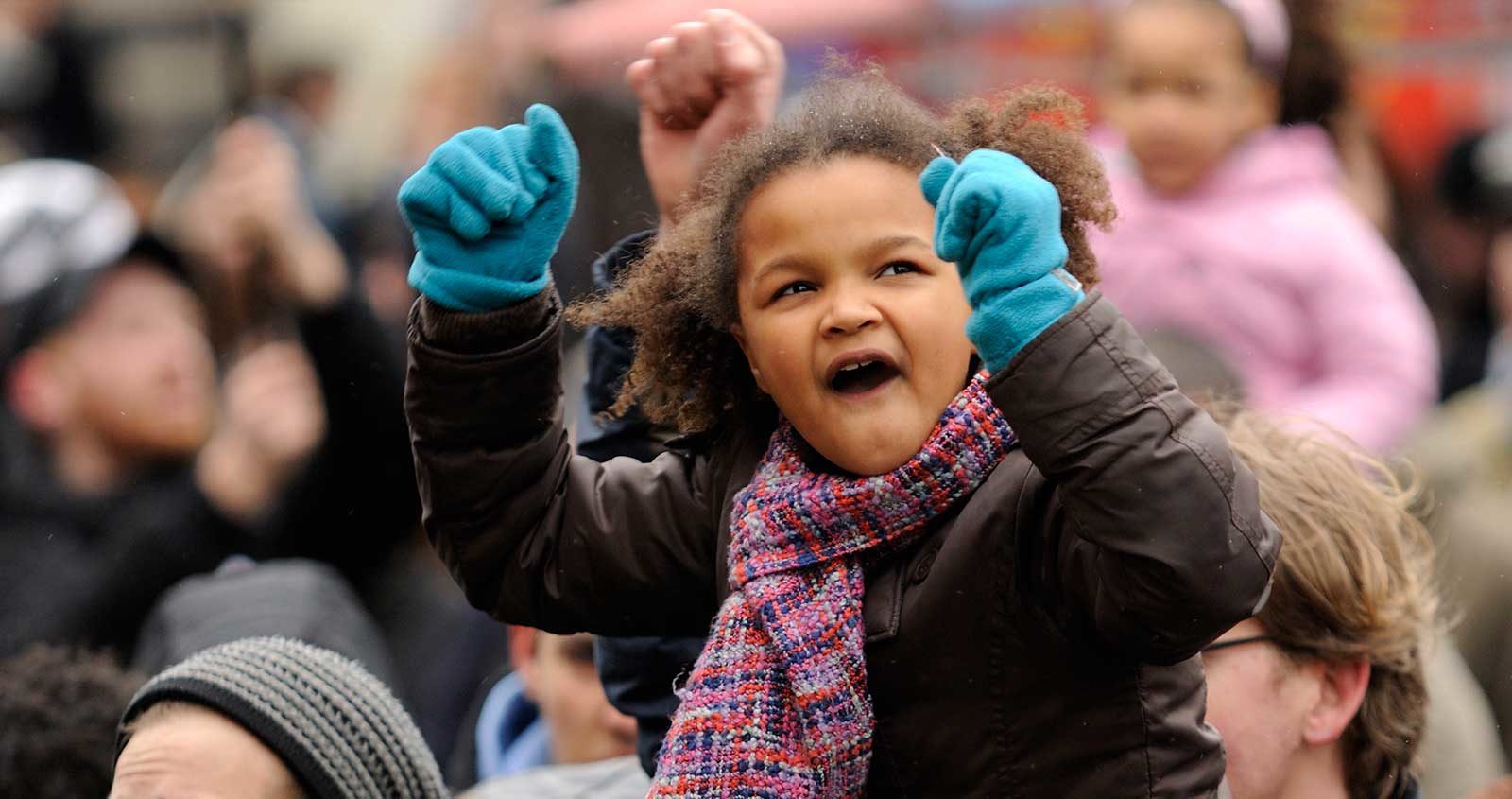 A girl with her fists in the air, on someon's shoulders in a protest