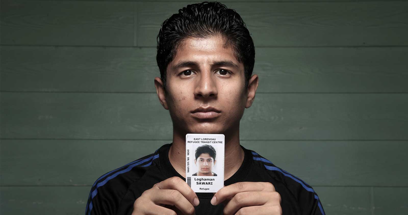 Refugee Loghaman Sawari holding an ID card
