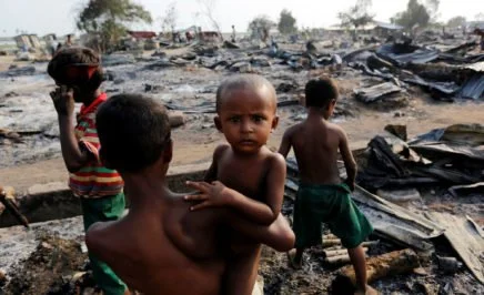 Boys stand among debris at a camp for displaced people, near Sittw