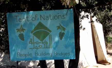 Tent of Nations sign on a fence. It is a blue sign that also says 