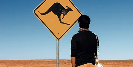 man stands infront of a kangaroo sign on a desert road