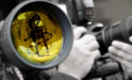 This is an image of a camera lens with a yellow Amnesty candle reflected in it. It was created as a youtube header image.