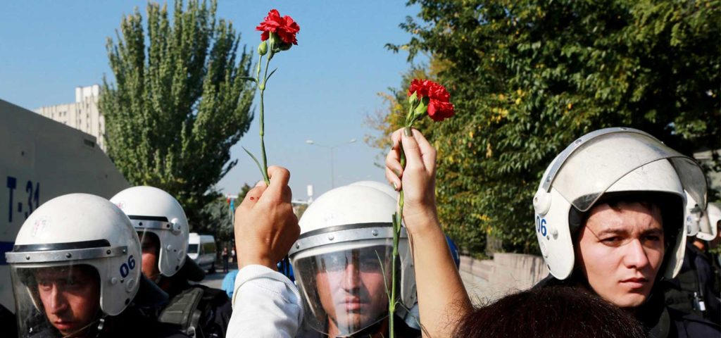 People hold carnations in front of riot police during clashes in Turkey