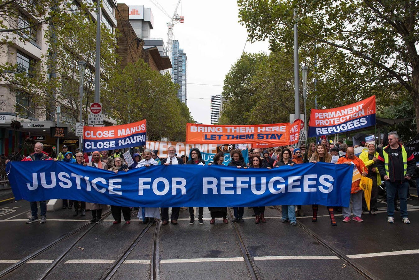 Protesters in Melbourne hold a blue banner that says 