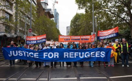 Protesters in Melbourne hold a blue banner that says 