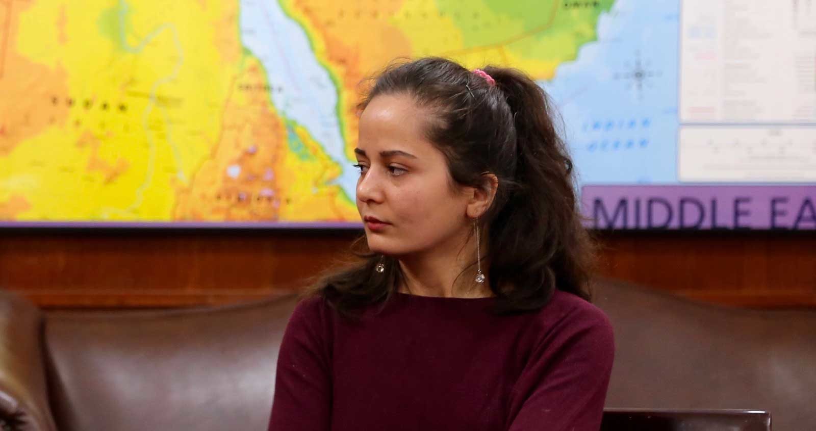 Suzanne Khoja sits in front of a map of the world