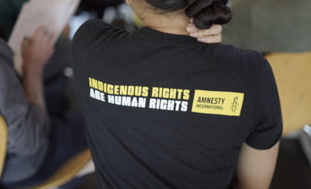 The back of a person's shirt that says 'Indigenous rights are human rights. Amnesty International'.