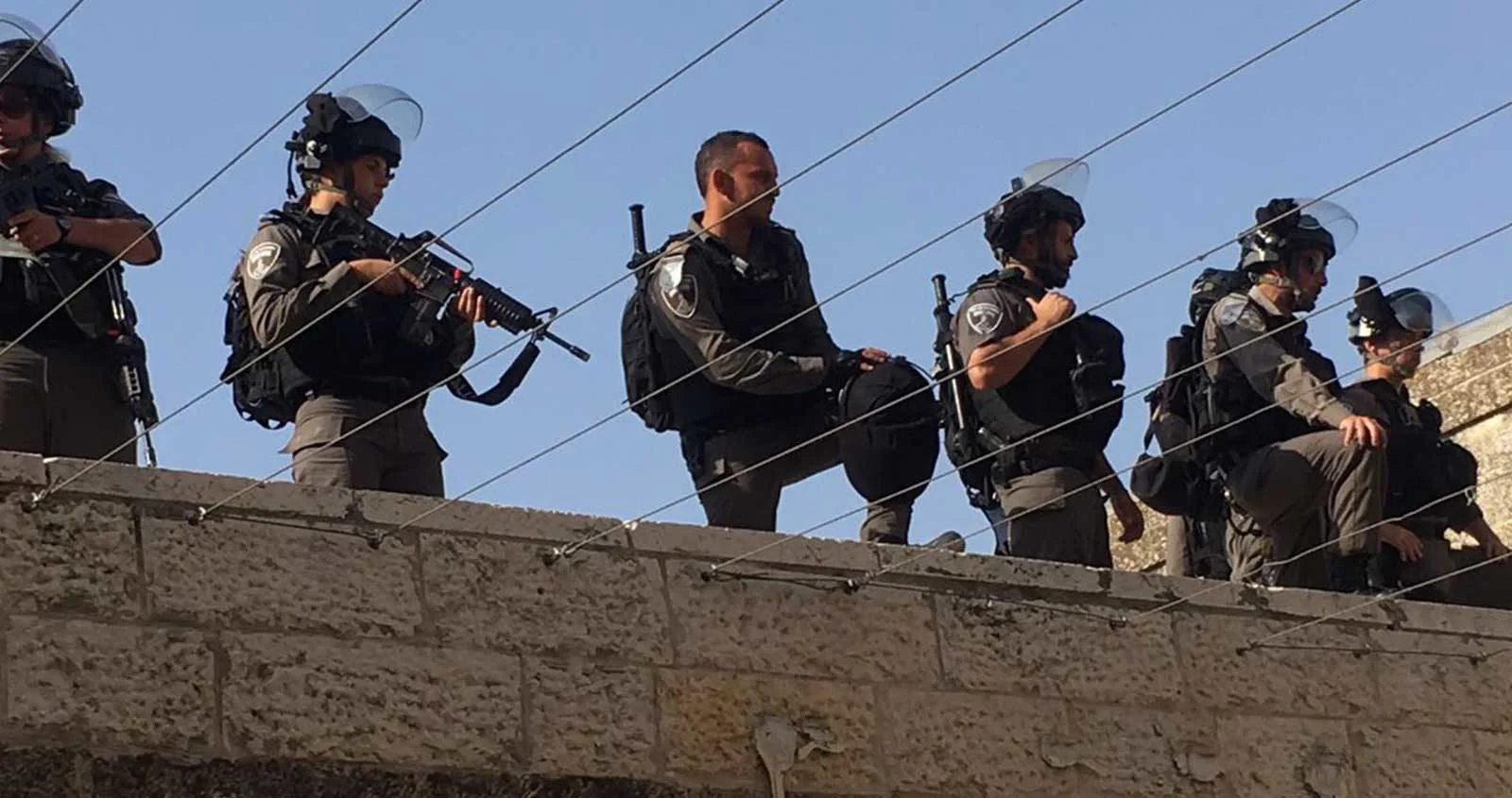 Armed guards stand on top of a wall.