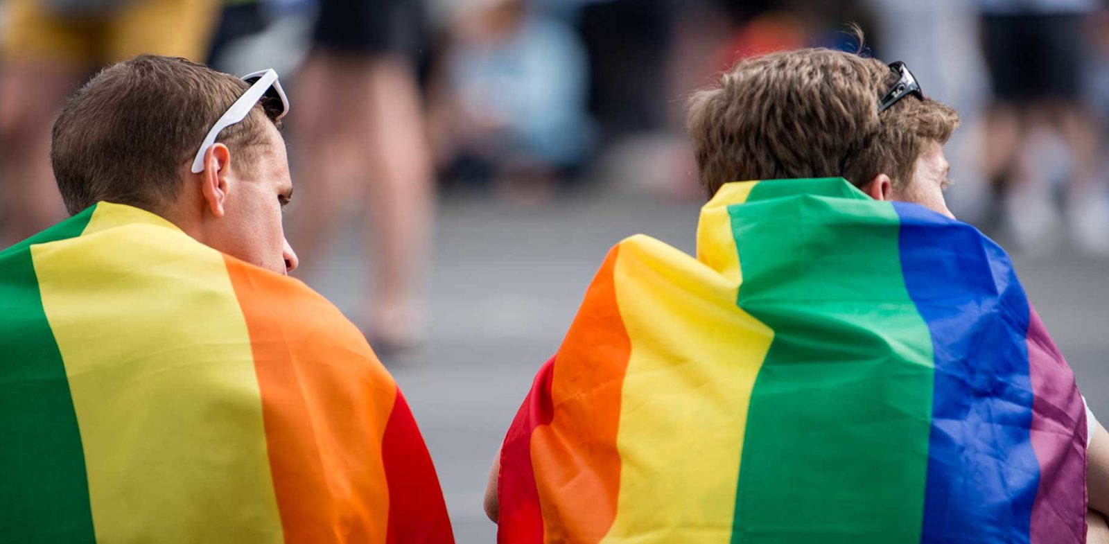 Two men wearing pride flags on their backs