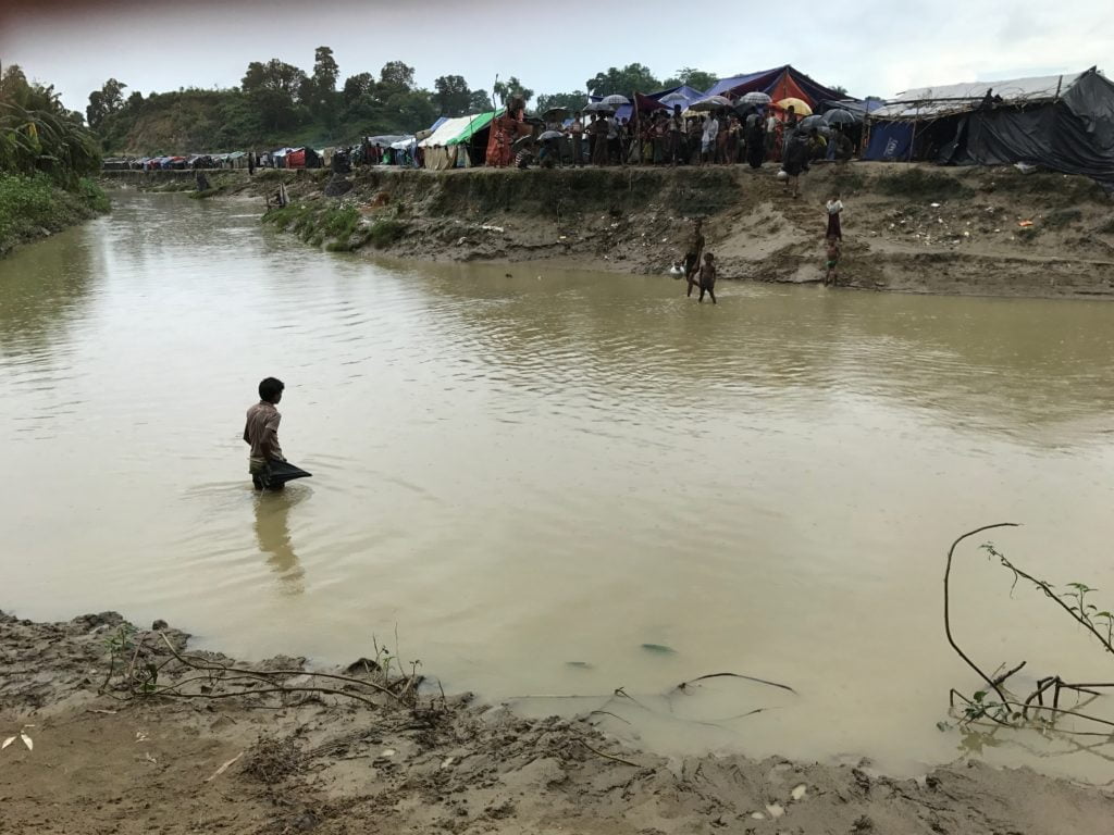 A Rohingya refugee wades in muddy water