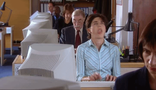 A gif of a woman typing at a computer and pulling a funny face. This is a scene from a UK comedy television show called 'Black Books'.